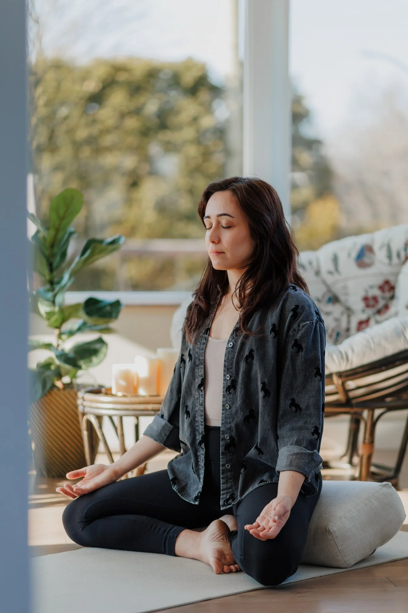 Woman sitting cross-legged with eyes closed during a quiet moment, photographed for a wellness brand session