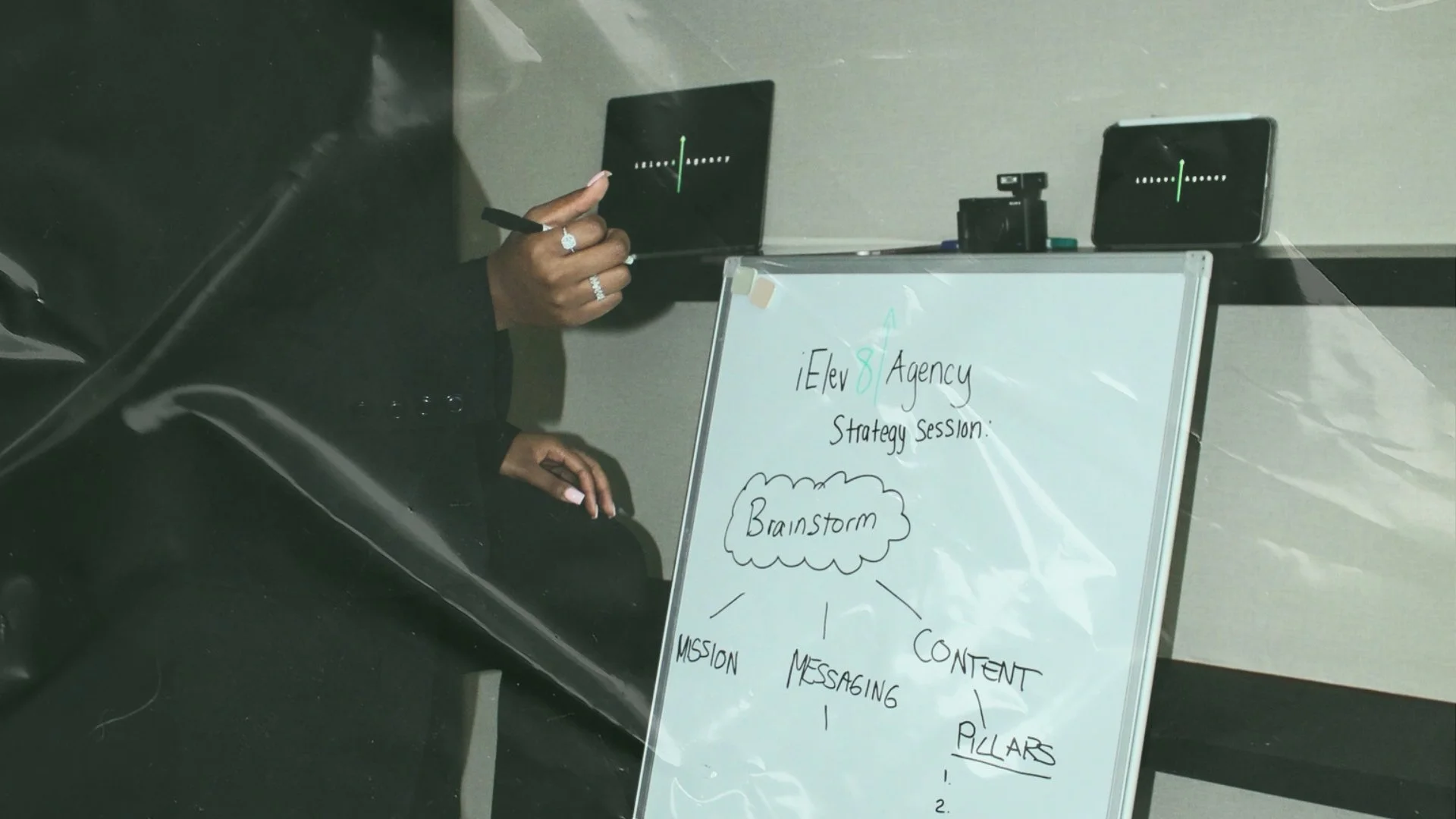 Person pointing at sticky notes on a whiteboard during a discussion or brainstorming session.