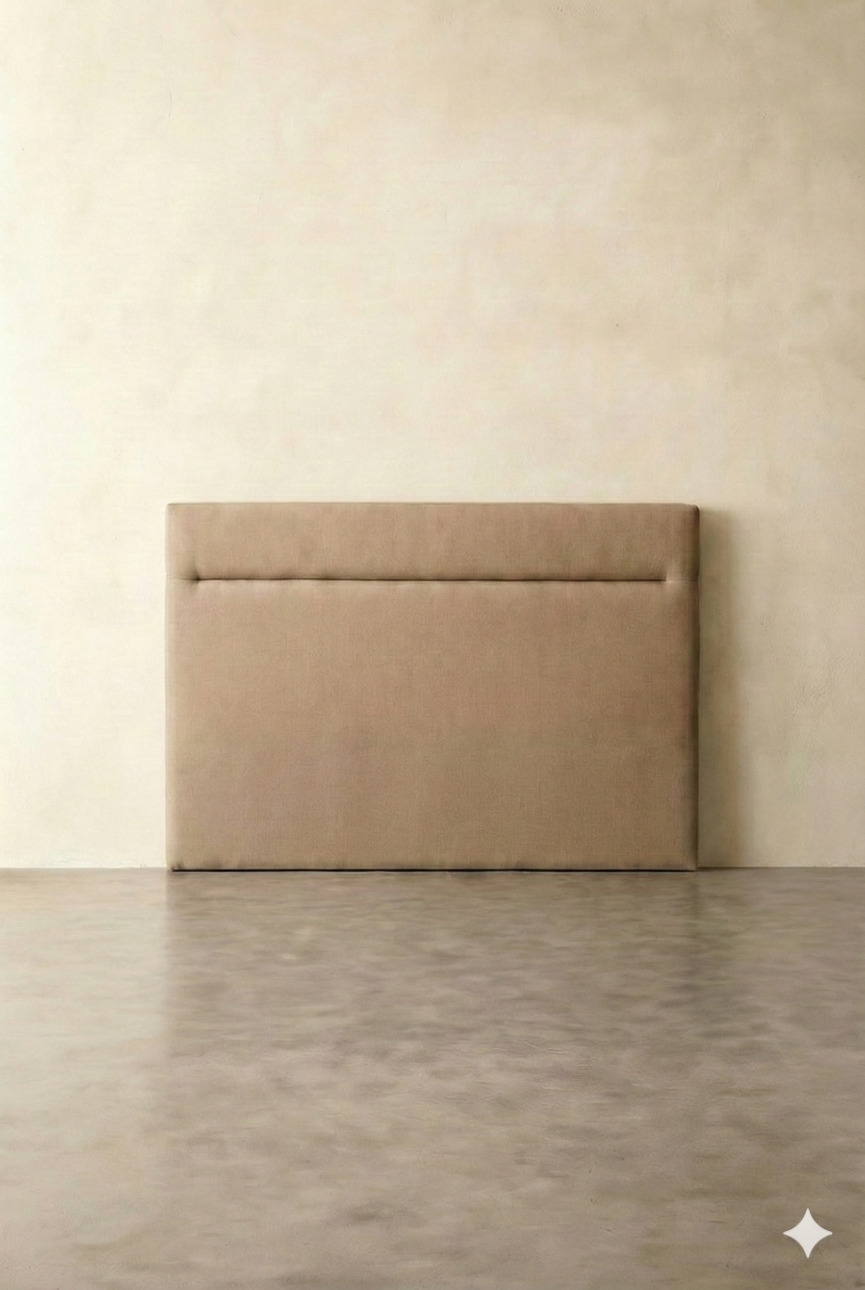 A beige upholstered bed headboard against a plain off-white wall on a light-colored floor.