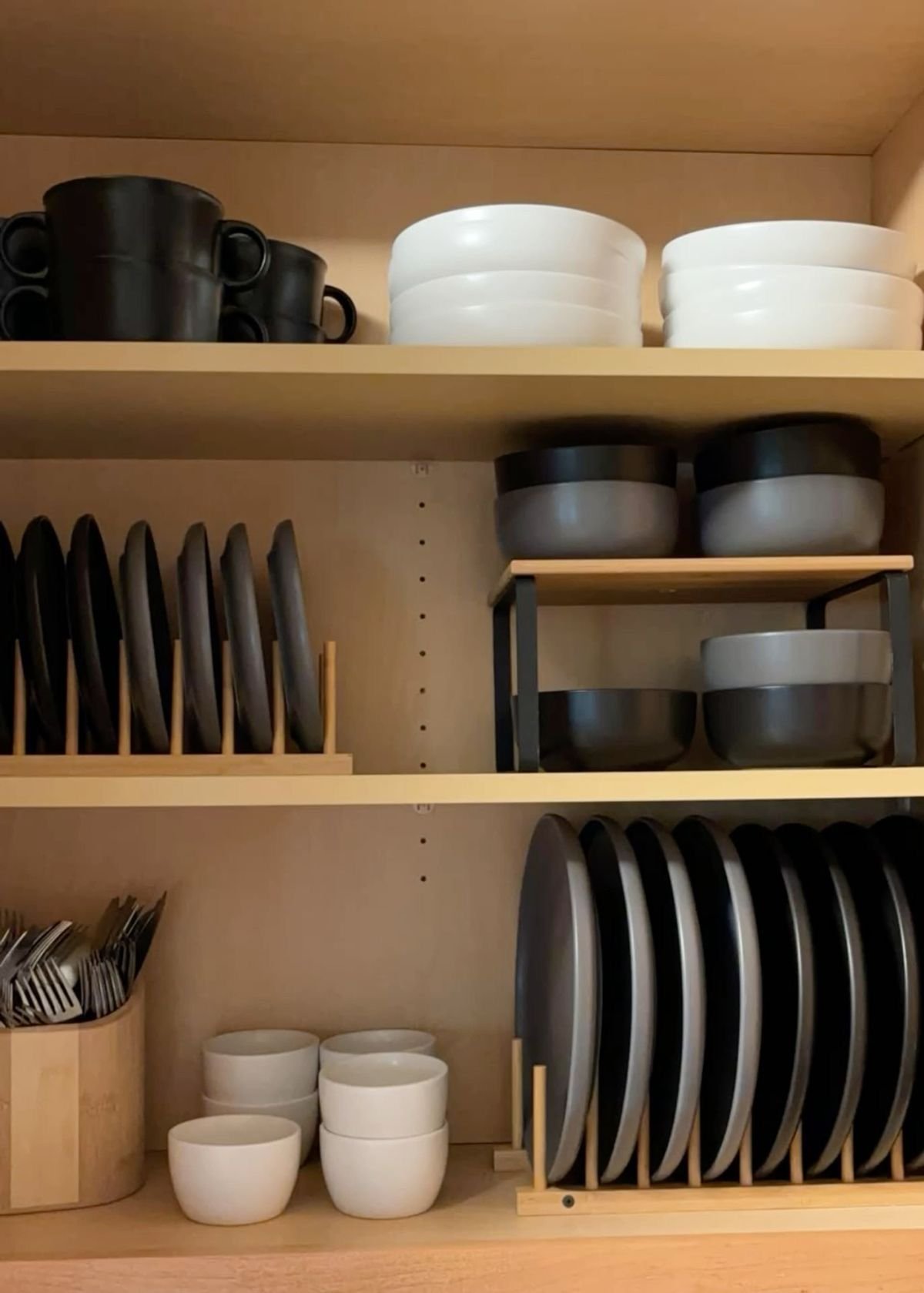 Kitchen cabinet with black and white dishes, bowls, and utensils neatly organized on shelves