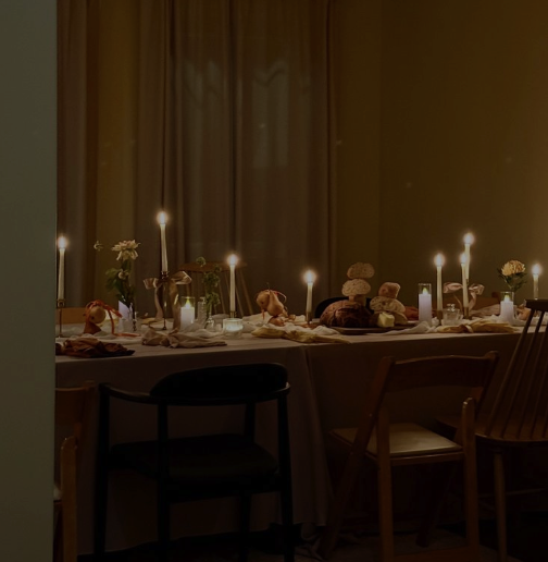 A dining table with candles and flowers, set for a meal in a dimly lit room.