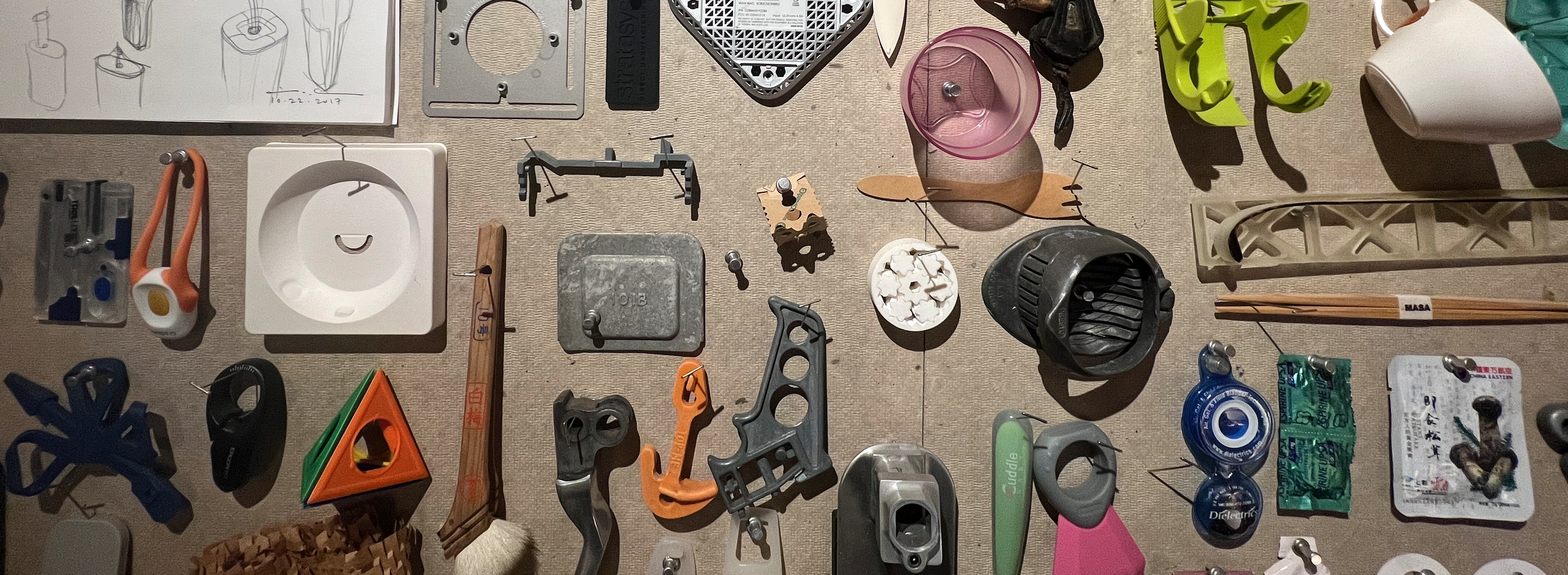 Various small objects and tools arranged on a flat surface, including a picture frame, a plastic cup, a flashlight, a small fan, a tape measure, a green plastic container, a pair of chopsticks, and other miscellaneous items.