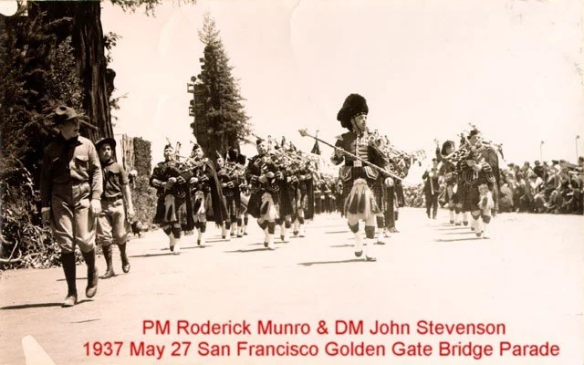 Black and white photo of a 1937 parade in San Francisco with soldiers marching, a bagpiper leading, and spectators along the side.