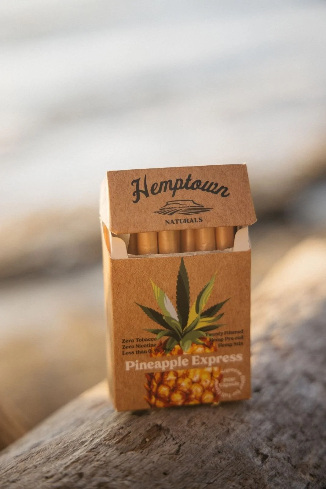 A small brown cardboard pack of HempTown Naturals Pineapple Express pre-rolled hemp cigarettes, featuring a pineapple and hemp leaf graphic on the front.