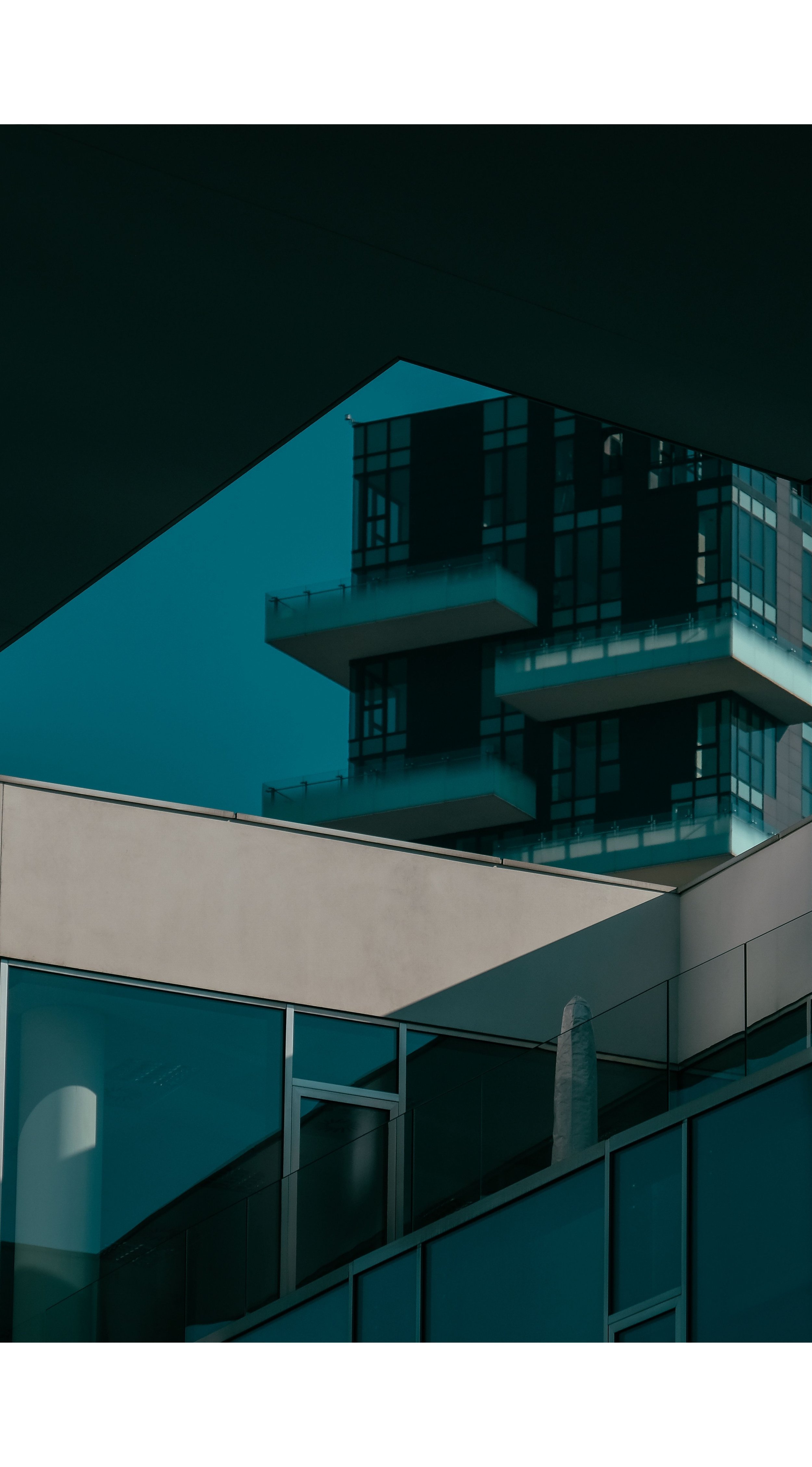 Modern architecture with glass buildings and geometric shapes, featuring balconies and reflective surfaces.