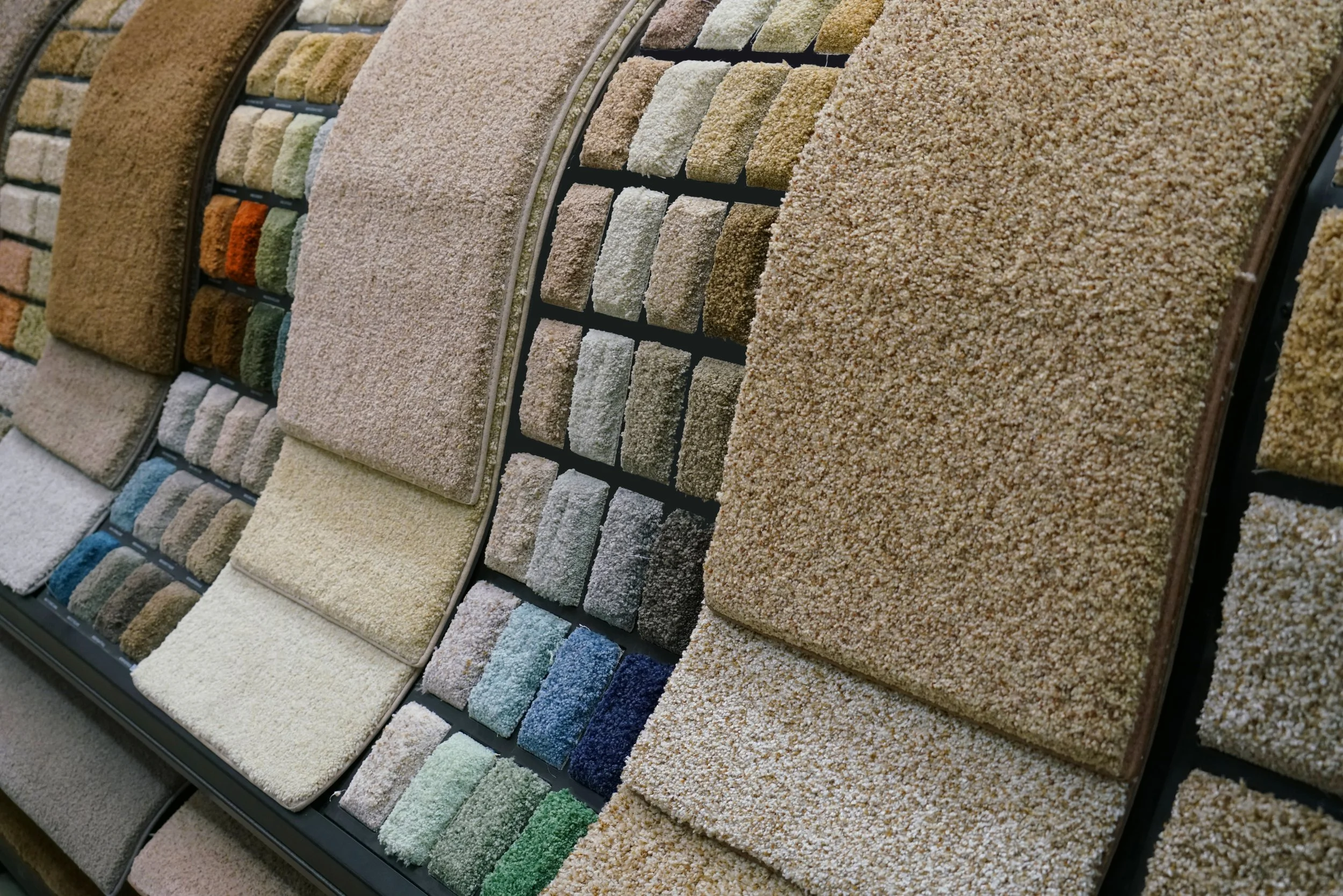 Display of various carpet samples in different colors and textures arranged in rows and sections.