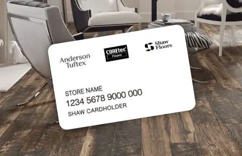 A white business card lying on a wooden floor with logos for Anderson Tuftex, CoreTec Floors, and Shaw Floors, and placeholder text for store name, account number, and cardholder name.
