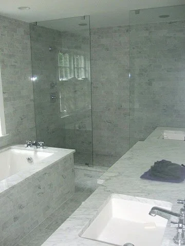 Bathroom with marble countertops, a built-in bathtub, and a glass-enclosed shower with tiled walls. Canda Construction residential construction and renovation.