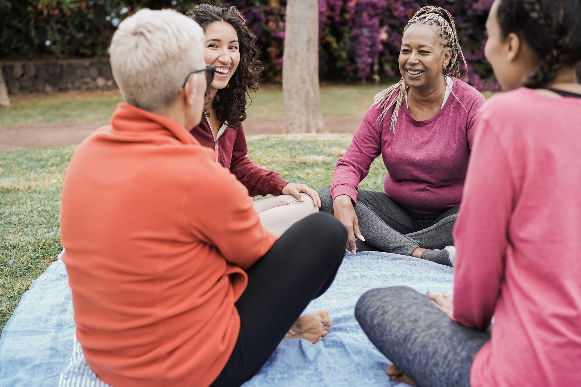 Women sitting together in a circle outdoors, representing CELE’s supportive and connected community.