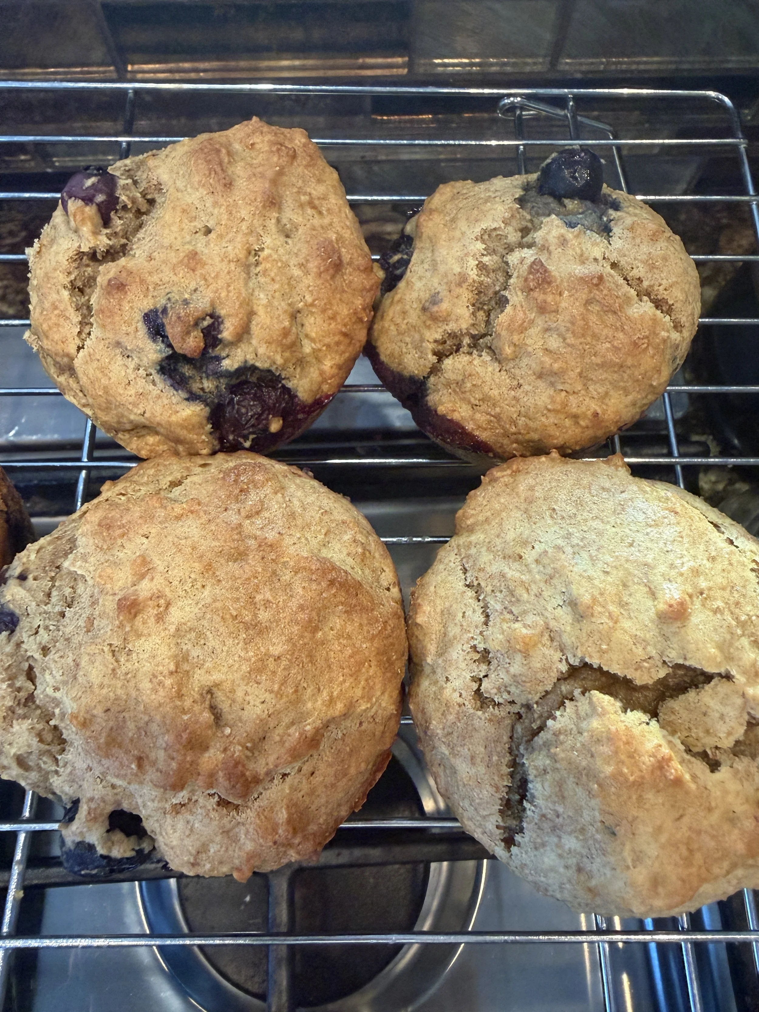 Four baked blueberry muffins on cooling rack