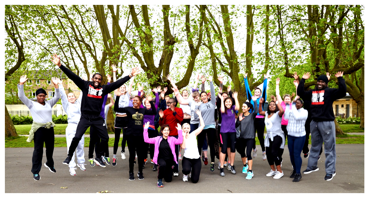 Group of people joyfully jumping outdoors in a park with green trees in the background