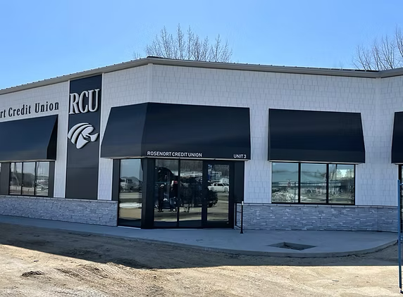 The exterior of a RCU Credit Union branch building with large black awnings and glass doors and windows.