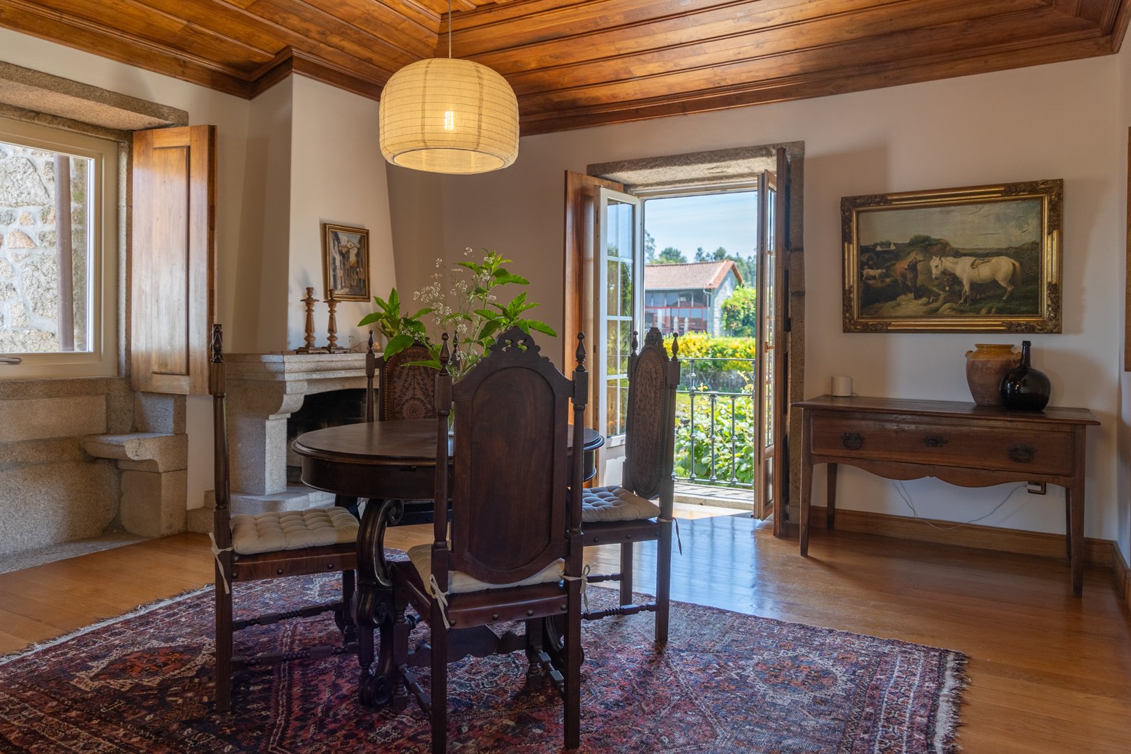 Dining room featuring authentic, rustic wooden ceiling and has a balcony which overlooks lush kiwi vines and terraced landscape.