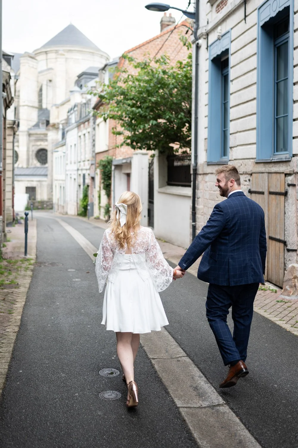 couple de mariés se tenant la main, se balade dans les ruelle d'Arras