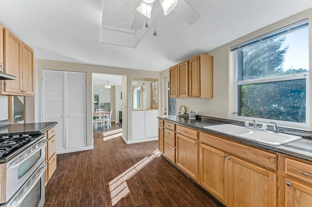 Kitchen with wooden cabinets, a large window, and a double sink.