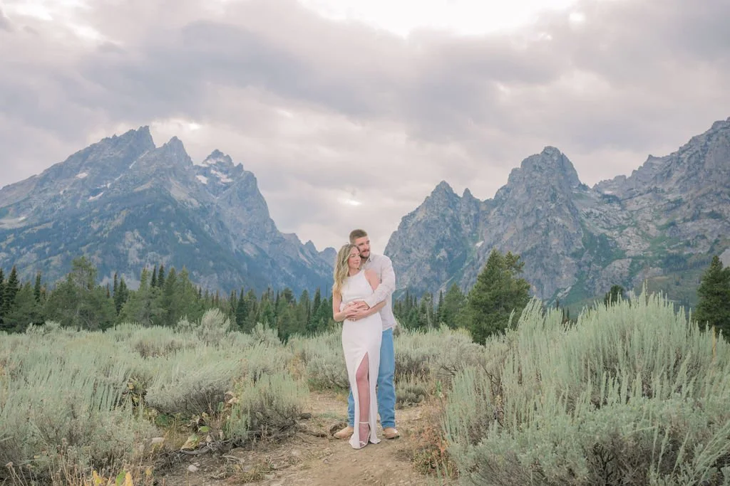 man and woman hugging with the Grand Tetons behind them
