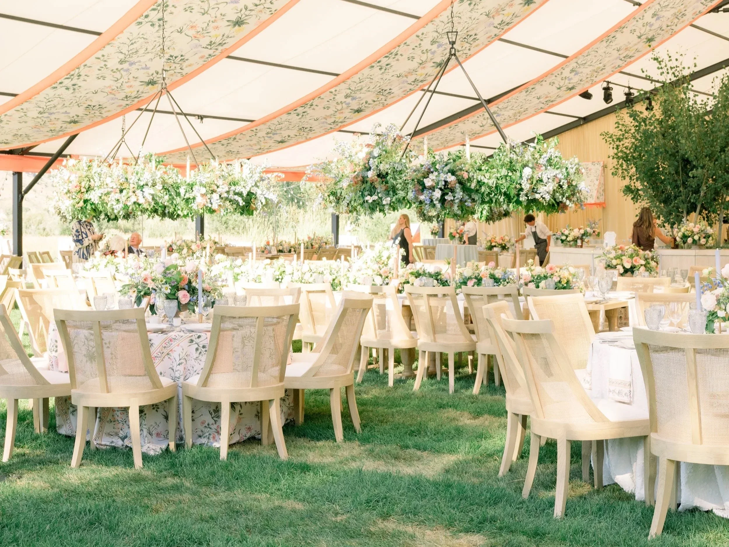 outdoor wedding with floral fabric on ceiling with floral chandeliers and table settings