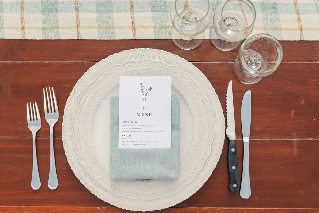 Table setting with plate, wedding invite, water classes, and a table runner