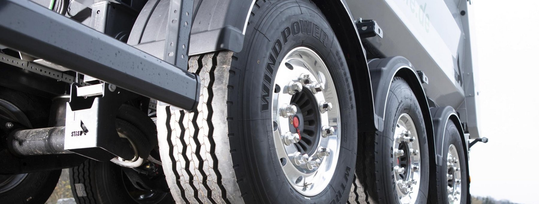 Close-up of truck tires, showing multiple large tires with polished rims and black tires labeled "WindPower."