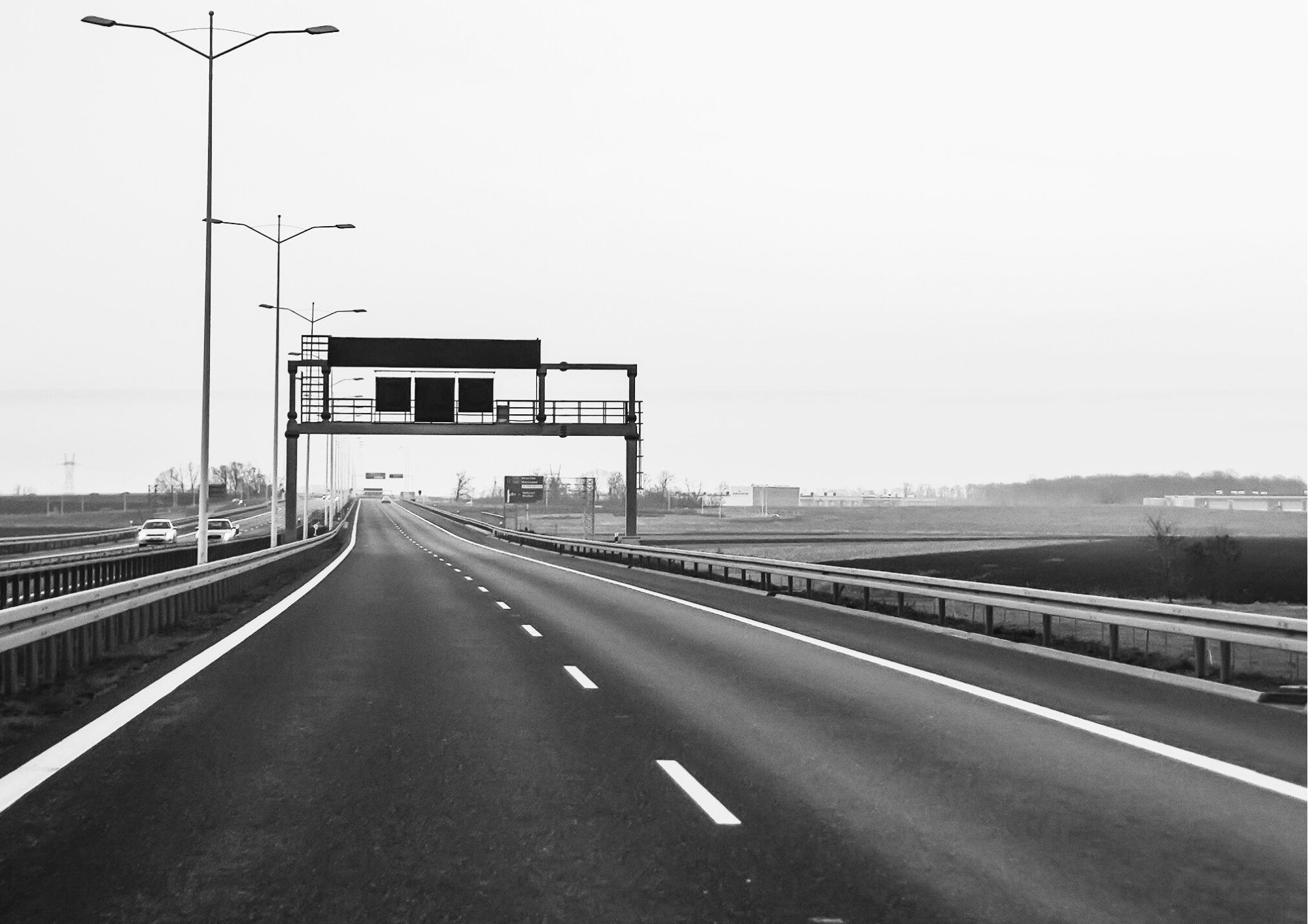 Empty highway with road signs and streetlights, black and white photo.