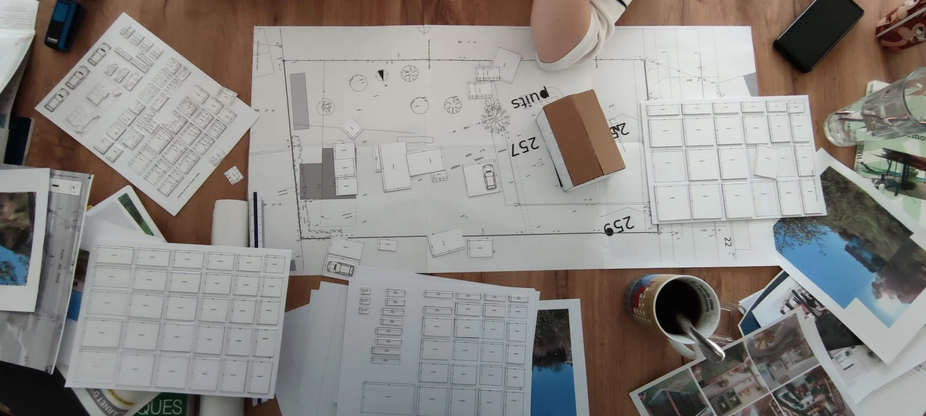Plan d'architecte avec maquettes et photos de projet sur une table