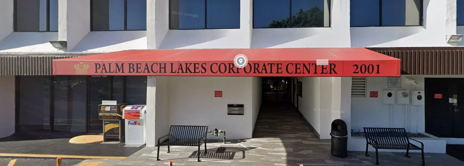 Entrance of Palm Beach Lakes Corporate Center with a red awning and benches outside. The address 2001 displayed on the awning.
