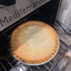 A freshly baked cheesecake in an oven, with a golden-brown crust.