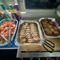 Buffet-style food with sliced roast beef, fried chicken, and a mixed vegetable salad.