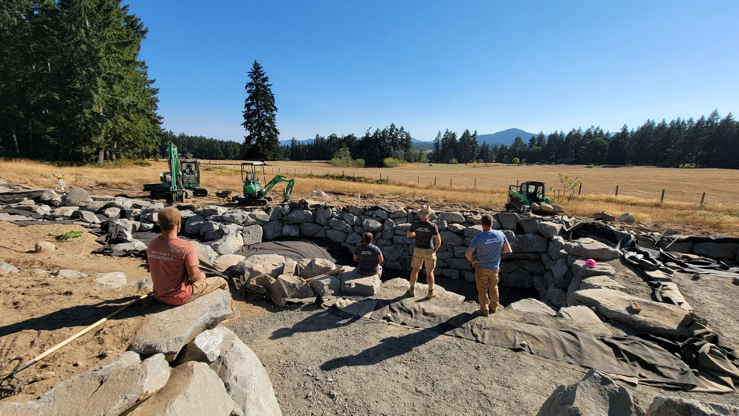 Team of natural pool builders on-site after completing a custom swimming pool