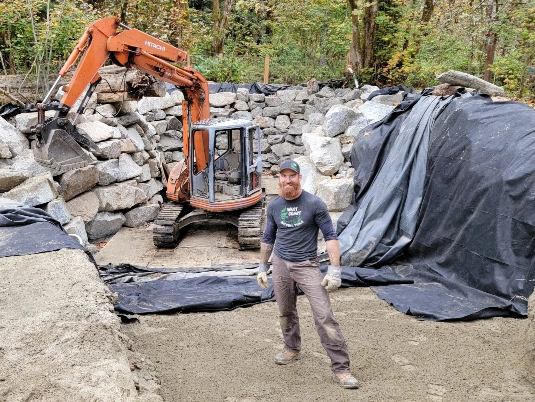 Founder Jeremiah standing in a natural swimming pool under construction, overseeing the build process