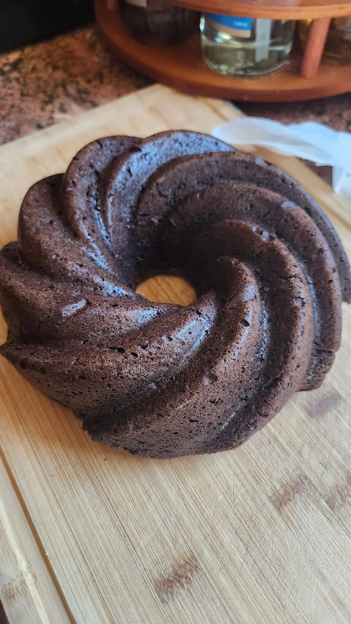 Chocolate bundt cake on a wooden cutting board.