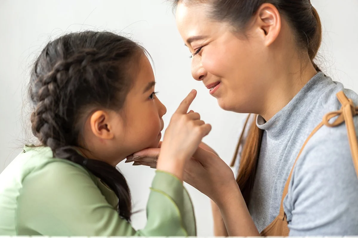 Mother and daughter looking into each other’s eyes, showing connection, playfulness, and supportive parent-child therapy