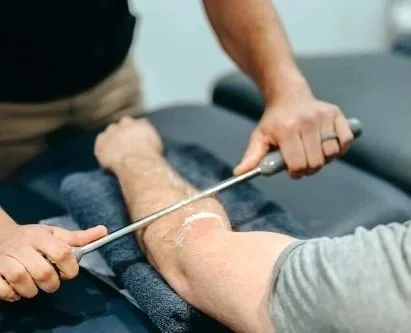 A healthcare professional performing ultrasound therapy on a patient's calf.