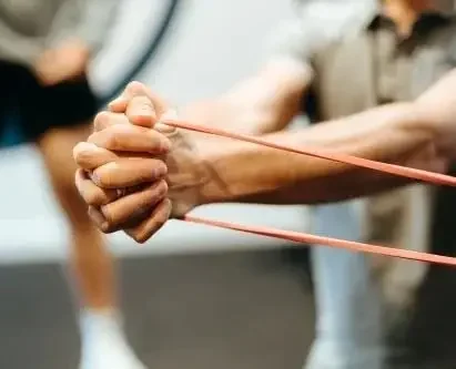 Person stretching their arm using a resistance band in a fitness class.