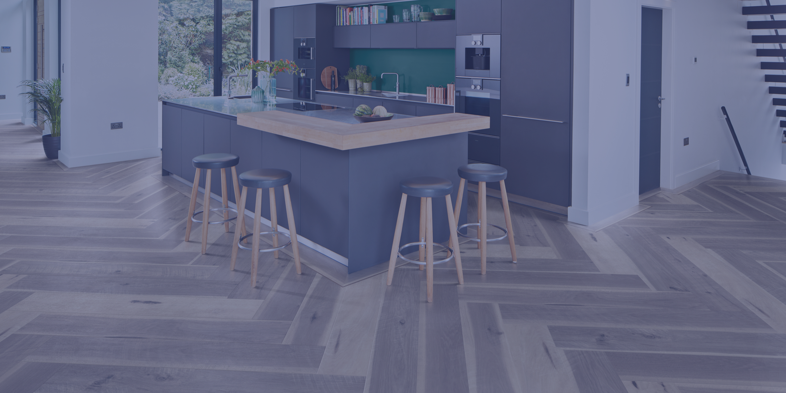 Modern kitchen with blue cabinets, a large island with a wooden countertop, four bar stools, and a spacious open layout.