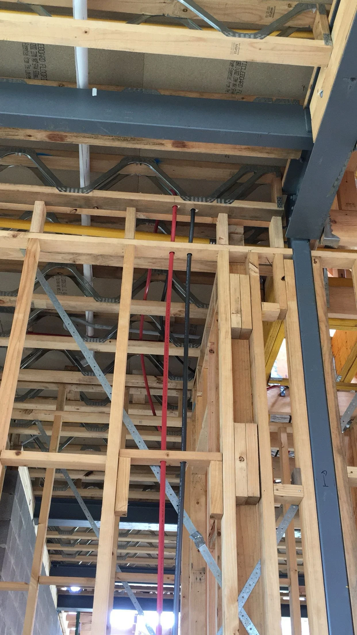 Construction site with wooden framing, metal supports, and red and black electrical conduits.