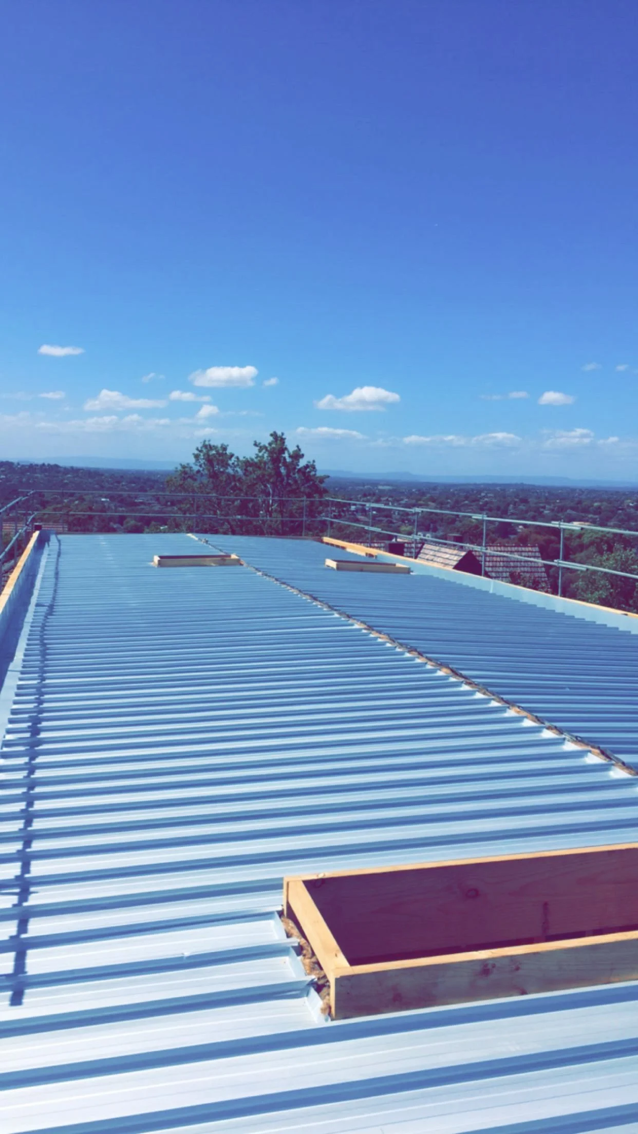 Metal roofing on a building under construction with a scenic view of the countryside and blue sky