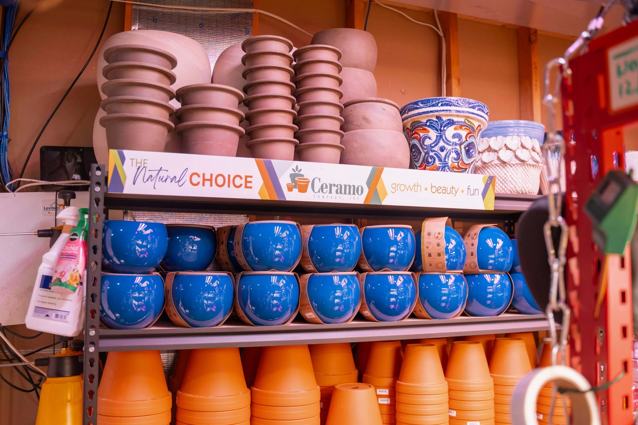 Shelves filled with colorful flower pots, including terracotta, blue, and decorative patterned ones, in a store aisle.