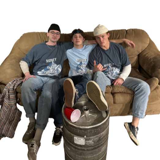Three young men sitting on a beige couch with a beer keg in front of them, all wearing blue shirts and casual pants, with two of them wearing hats.