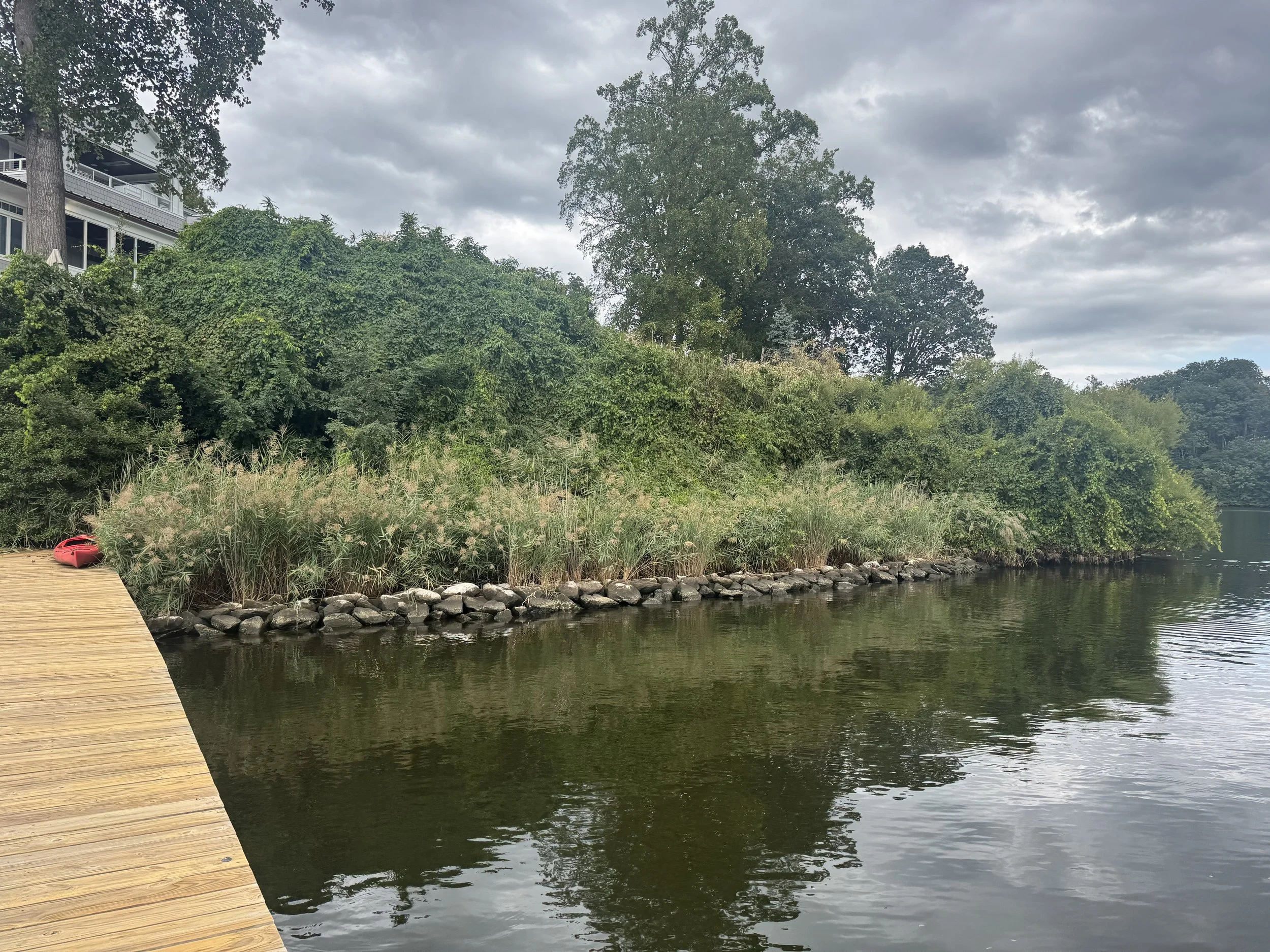 Scenic landscape of mountains, a lake, and rolling green fields under a cloudy sky.