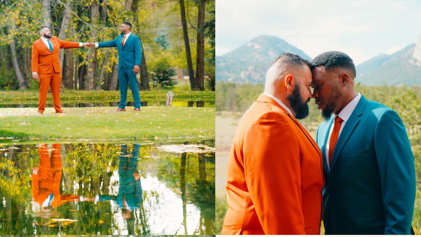 Two men in colorful suits holding hands and touching foreheads outdoors in a mountainous landscape, with a reflection of them in a pond.