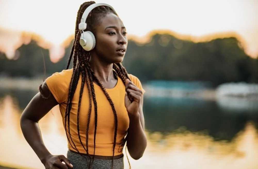 A girl with headphones running down a sidewalk
