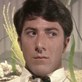 Close-up of a man with dark hair and a serious expression, dressed in a white shirt, in an indoor setting with a plant and candles in the background. The Graduate.
