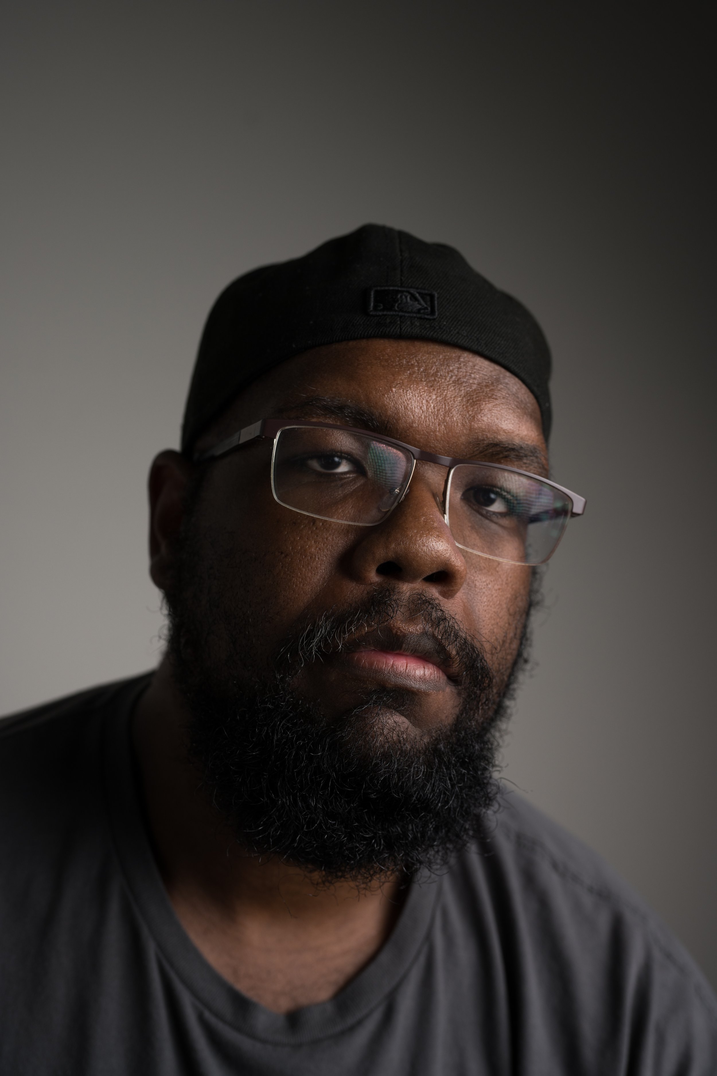 Darius Livingston, Producer of "The Tooth Fairy" short film. Close-up portrait of a man with glasses, a black cap, and a beard, looking at the camera with a serious expression, against a plain background.