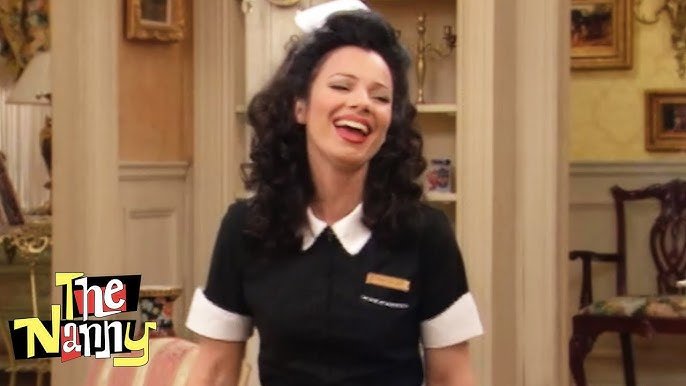 A woman with dark curly hair, wearing a black uniform with white trim, smiling and laughing in a living room setting. The Nanny, Fran Drescher. 