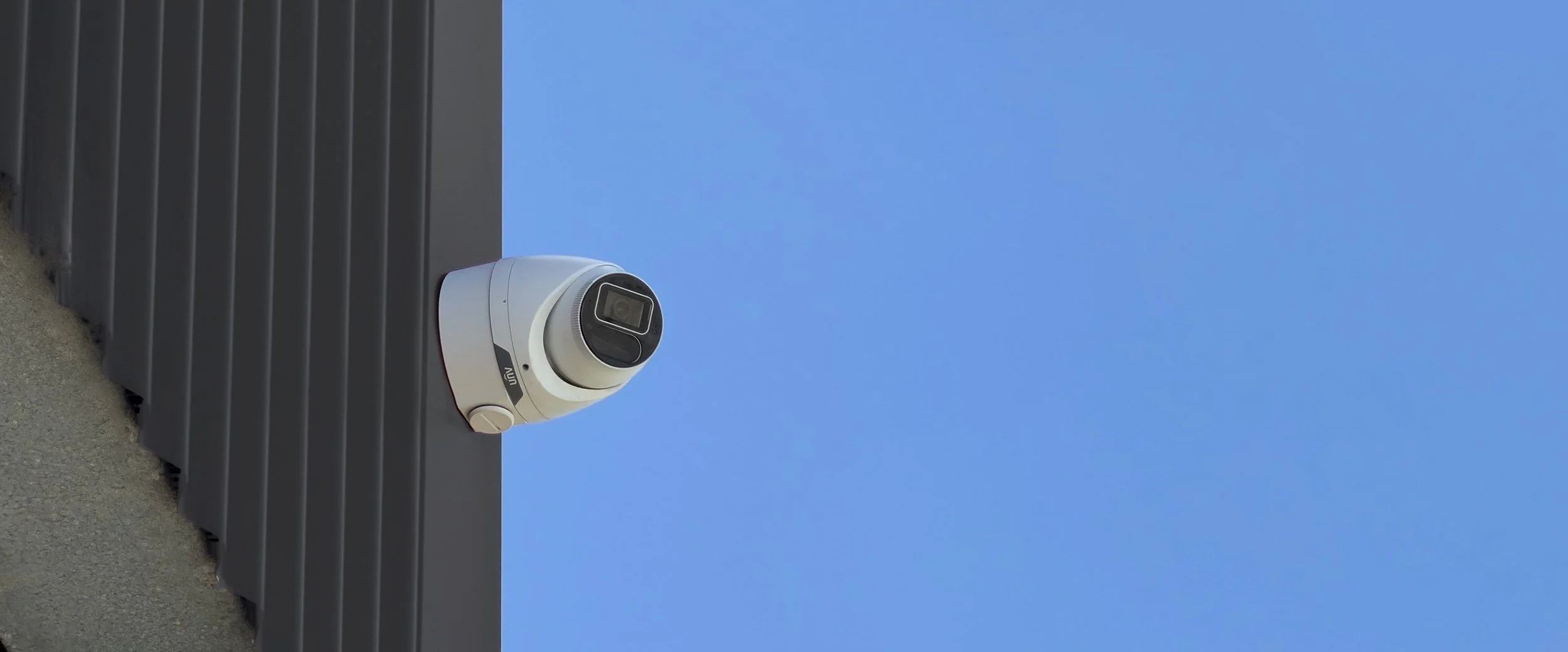 Turret security camera mounted on dark cladding