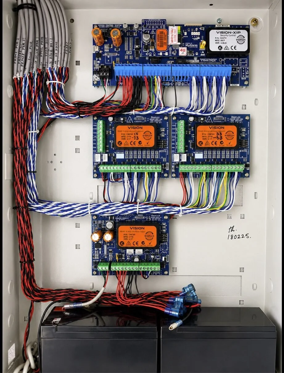 Digiflex alarm panel installed by Panther Security, with neatly looped cabling and backup batteries
