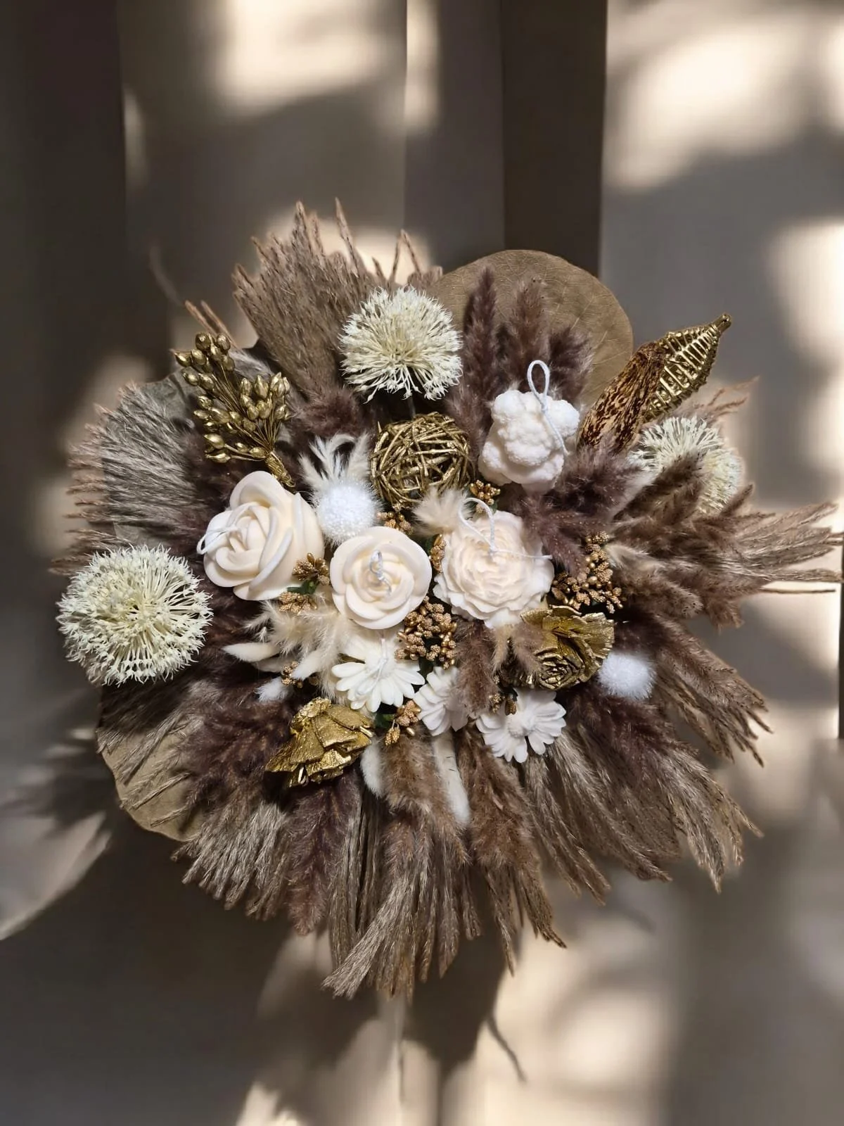 Ein Blumenarrangement aus diversen Kerzen Blumen, Federn, Bommeln und dekorativen Objekten in neutralen Tönen