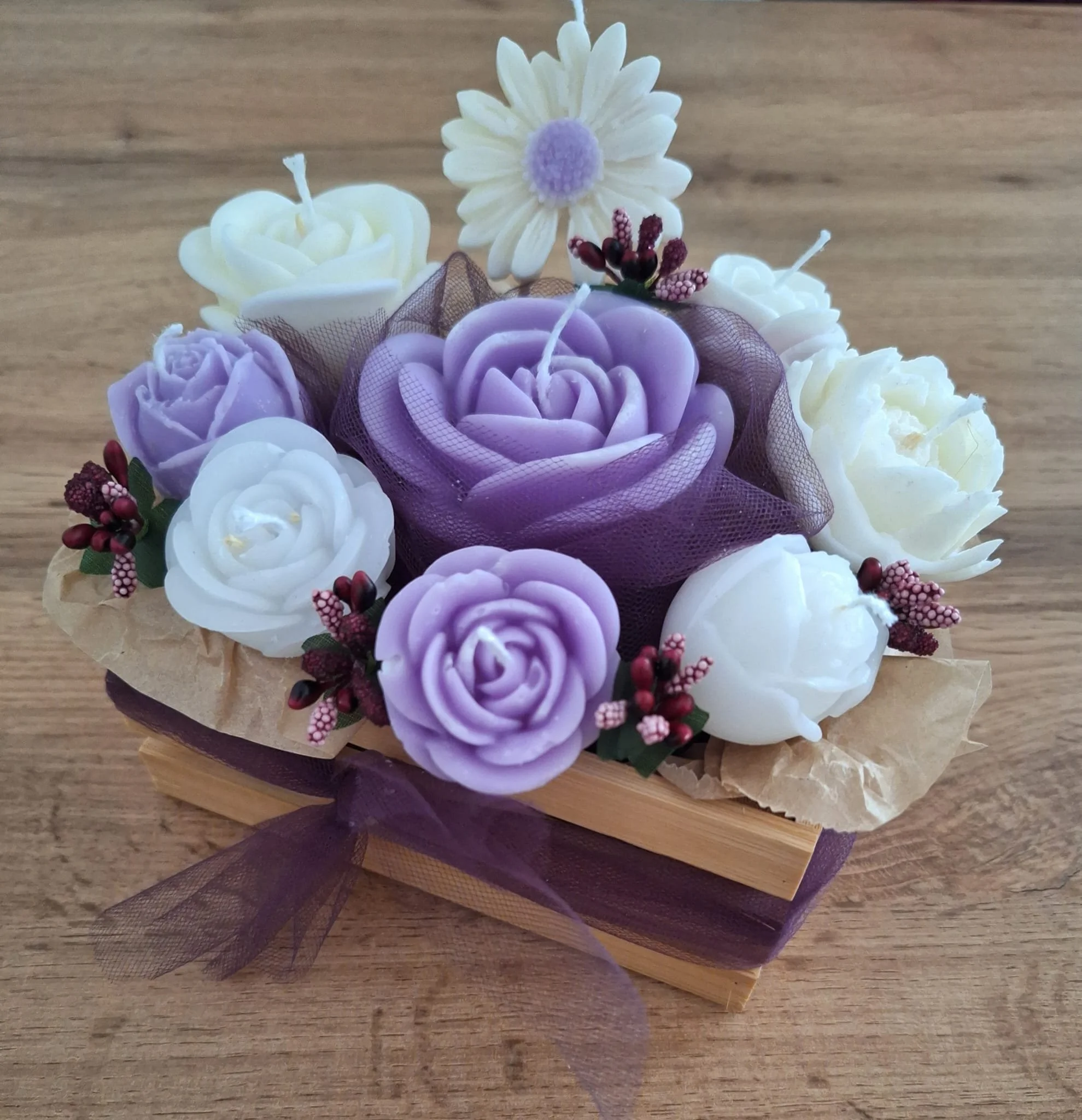 Dekorative Blumenkerze in einer Geschenkbox, mit weißen, lilafarbenen und cremefarbenen Blumen und einem lila Schleifenband