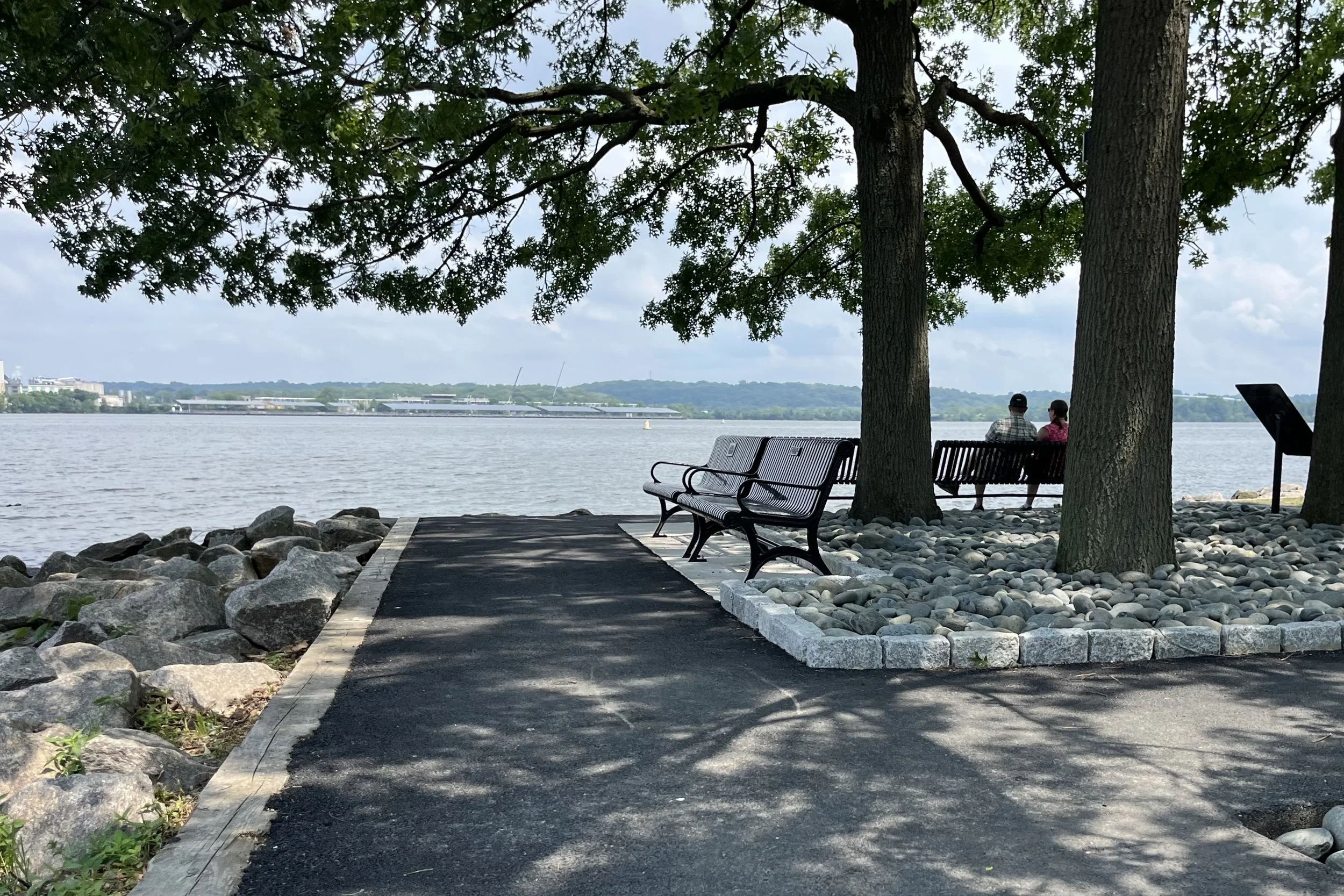 Shaded walking path through Tide Lock Park overlooking the Potomac River in Old Town Alexandria.
